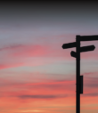directional sign in front of sunset